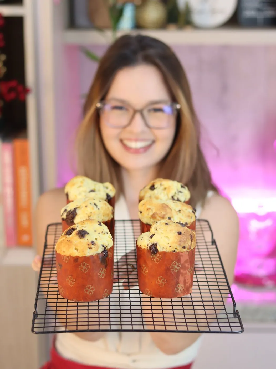 Chef Laíse Lopes sorrindo e segurando uma grade com panetones zero